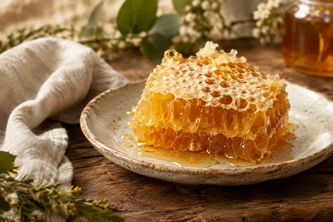 Miel ambré dans ses alvéoles de cire, servi sur une assiette en céramique artisanale